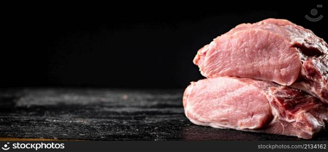 Pieces of raw pork on the table. On a black background. High quality photo. Pieces of raw pork on the table.