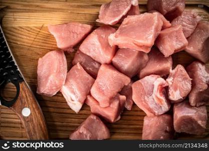 Pieces of raw pork with a knife. On a wooden background. High quality photo. Pieces of raw pork with a knife.