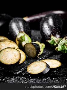 Pieces of ripe eggplant on a stone board. On a black background. High quality photo. Pieces of ripe eggplant on a stone board. 