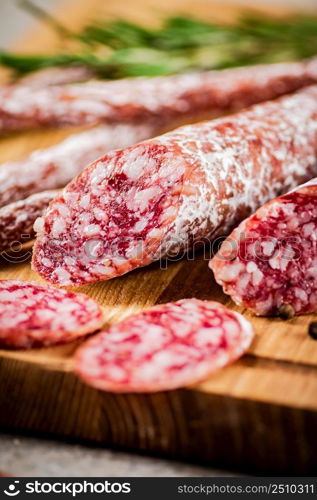 Pieces of salami sausage on a cutting board. On a rustic background. High quality photo. Pieces of salami sausage on a cutting board.