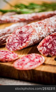 Pieces of salami sausage on a cutting board. On a rustic background. High quality photo. Pieces of salami sausage on a cutting board.