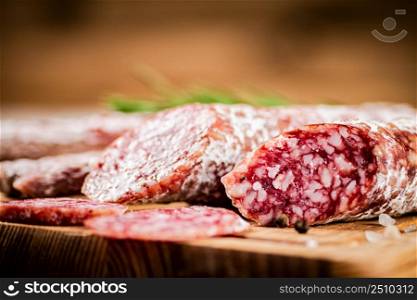 Pieces of salami sausage on a cutting board. On a rustic background. High quality photo. Pieces of salami sausage on a cutting board.