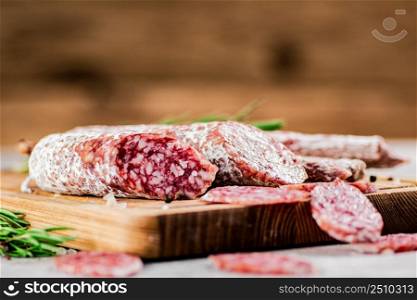Pieces of salami sausage on a cutting board. On a rustic background. High quality photo. Pieces of salami sausage on a cutting board.