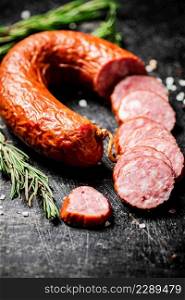 Pieces of salami sausage with a sprig of rosemary. On a black background. High quality photo. Pieces of salami sausage with a sprig of rosemary.