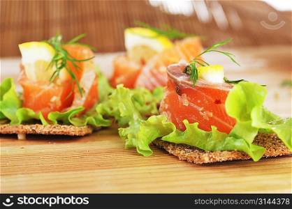 pieces of salmon with lemon lettuce and small loafs