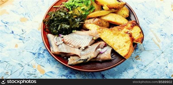 Pieces of salted herring with baked potatoes and toast.. Tasty salted herring fish