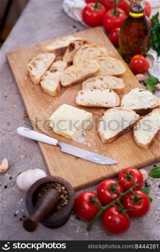pieces of sliced baguette with spread butter on wooden board.. pieces of sliced baguette with spread butter on wooden board
