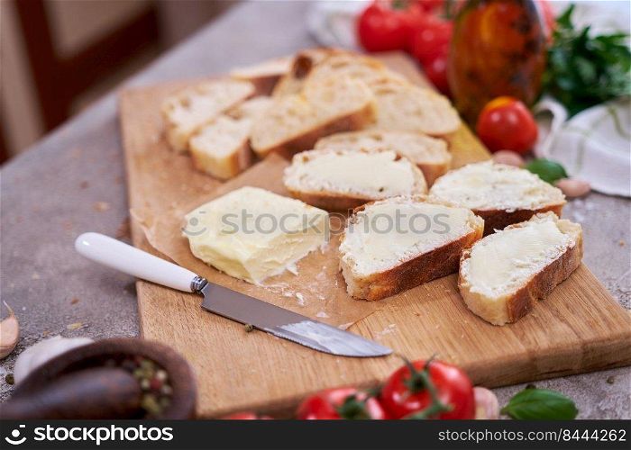 pieces of sliced baguette with spread butter on wooden board.. pieces of sliced baguette with spread butter on wooden board
