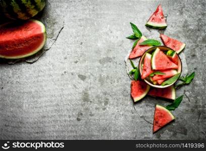 Pieces of watermelon in a bowl with mint. On the stone table.. Pieces of watermelon in a bowl with mint.