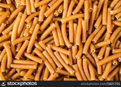 Pieces of Wholewheat macaroni fill the frame as these brown tubes are viewed up close.