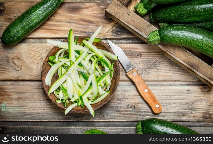 Pieces of zucchini in a bowl and whole zucchini tray. On wooden background. Pieces of zucchini in a bowl and whole zucchini tray.