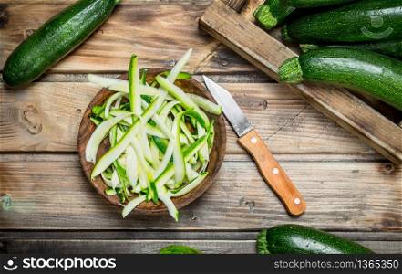 Pieces of zucchini in a bowl and whole zucchini tray. On wooden background. Pieces of zucchini in a bowl and whole zucchini tray.