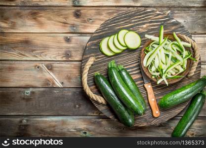 Pieces of zucchini in a bowl on a cutting Board with a knife. On wooden background. Pieces of zucchini in a bowl on a cutting Board with a knife.