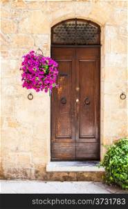 Pienza, Tuscany region, Italy. Old door made of wood with flowers