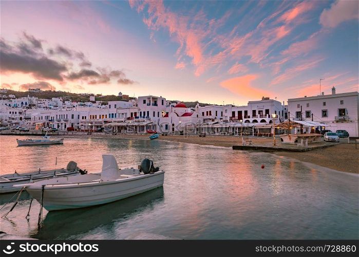 Pier with fishing boats, church and town hall at sunrise in Old Port of Mykonos City, Chora, on the island Mykonos, Greece. Old harbour in Mykonos, Greece