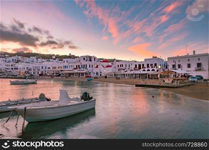 Pier with fishing boats, church and town hall at sunrise in Old Port of Mykonos City, Chora, on the island Mykonos, Greece. Old harbour in Mykonos, Greece