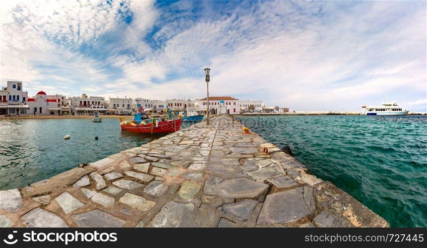 Pier with fishing boats, church and town hall in Old Port of Mykonos City, Chora, on the island Mykonos, Greece. Old harbour in Mykonos, Greece