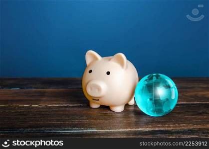 Piggy bank and blue earth globe. World financial system. Payment services, international money transfers. financial flows. Protection of savings from inflationary risks. Investments in other countries