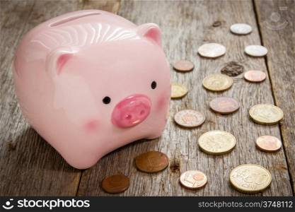 Piggy bank and coins on the wooden background