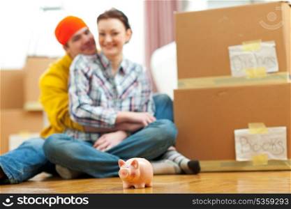 Piggy bank and young family among boxes in background