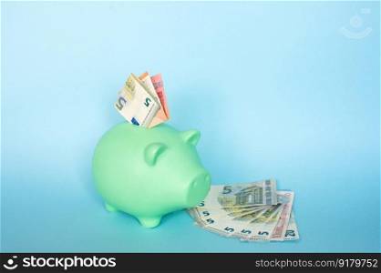 Piggy bank highlighted on a blue background.. 5 and 10 euro notes on a blue background in a piggy bank