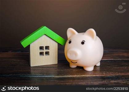 Piggy bank near a house. Savings on household bills, energy saving technologies. Save up for a new house. Mortgage loan. Maintenance, property improvement. Real estate market. Buying or selling.