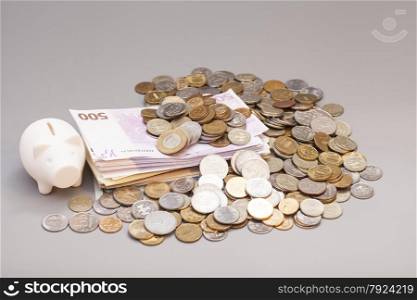 piggy bank with banknotes and coins on gray background