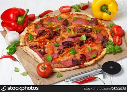 Piiza with a lot of ingredients and pizza cutter knife on wooden table still-life
