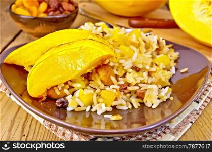 Pilaf fruit with pumpkin, raisins, dried apricots in a brown plate on a napkin, pumpkin, dried fruits on a wooden boards background