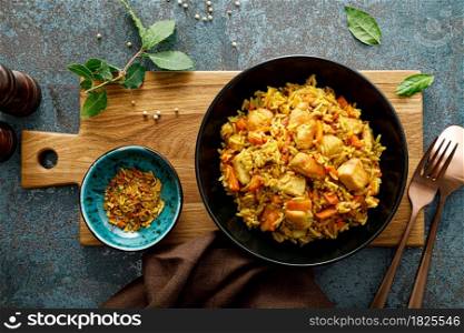 Pilaf or pilau with chicken, traditional uzbek hot dish of boiled rice, chicken meat, vegetables and spices on plate, top view.