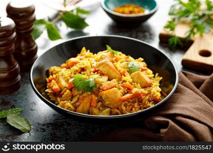 Pilaf or pilau with chicken, traditional uzbek hot dish of boiled rice, chicken meat, vegetables and spices on plate.