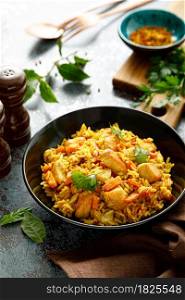 Pilaf or pilau with chicken, traditional uzbek hot dish of boiled rice, chicken meat, vegetables and spices on plate.