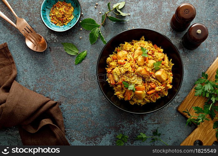 Pilaf or pilau with chicken, traditional uzbek hot dish of boiled rice, chicken meat, vegetables and spices on plate, top view.