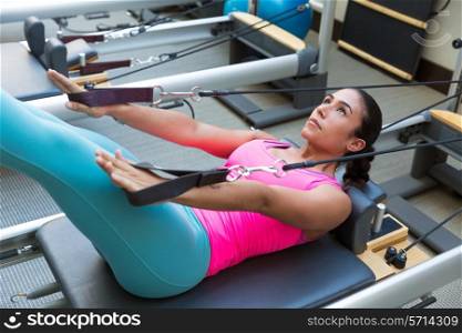 Pilates reformer workout exercises woman brunette at gym indoor