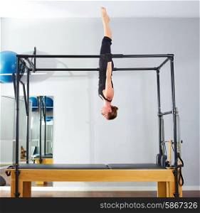 Pilates woman in cadillac acrobatic upside down balance reformer exercise at gym