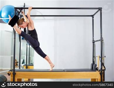 Pilates woman in cadillac split legs stretch exercise at gym