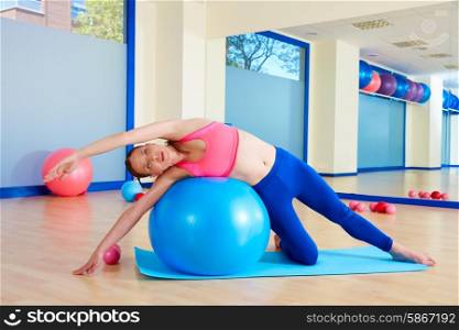 Pilates woman side bend fitball exercise workout at gym indoor swiss ball