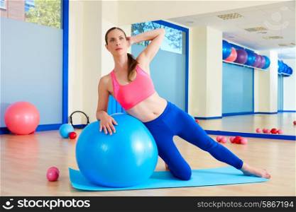 Pilates woman side bend fitball exercise workout at gym indoor swiss ball