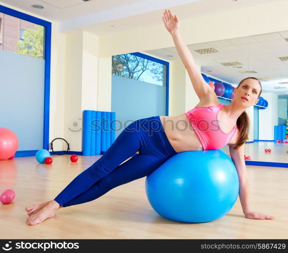 Pilates woman side bend fitball exercise workout at gym indoor swiss ball