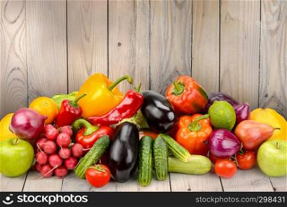 Pile fruits and vegetables on wooden table on background wooden wall. Copy space
