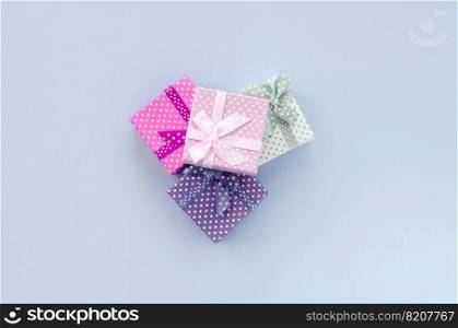 Pile of a small colored gift boxes with ribbons lies on a violet background. Minimalism flat lay top view.. Pile of a small colored gift boxes with ribbons lies on a violet background