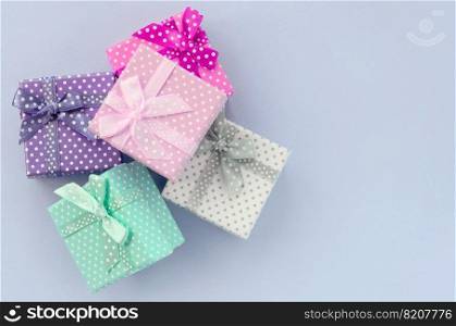 Pile of a small colored gift boxes with ribbons lies on a violet background. Minimalism flat lay top view.. Pile of a small colored gift boxes with ribbons lies on a violet background