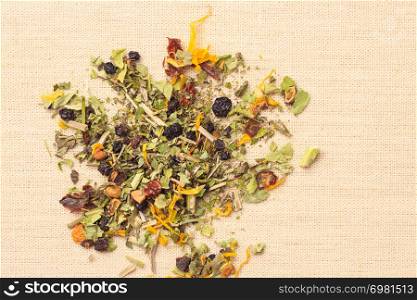 Pile of assorted natural medical dried herb leaves and fruits on burlap surface. Herbaceous plant.. Pile of dry herb leaves and fruits
