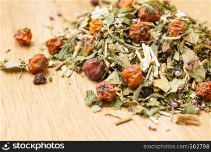 Pile of assorted natural medical dried herb leaves and fruits on wooden surface. Herbaceous plant.. Pile of dry herb leaves and fruits