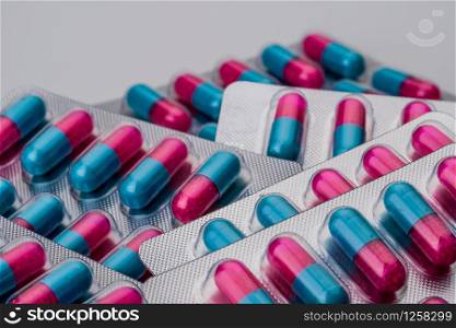 Pile of blue, pink capsule with granule in side pills. Pills in blister pack on white background. Pharmaceutical dosage form and packaging. Anti-fungal medicine.