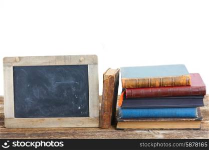 Pile of books. Pile of books on wooden table with empty blackboard isolated on white background