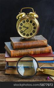 pile of books with clock. pile of old books with alarm clock