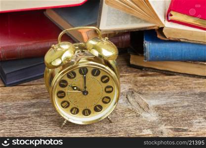 pile of books with clock. pile of old books with antique alarm clock