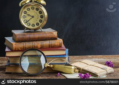 pile of books with clock. pile of old books with vintage alarm clock an looking glass