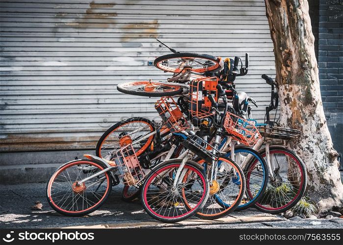 Pile of broken electric bikes on the sidewalk, Hangzhou, China. Infrastructure and regulations were not prepared to handle a sudden flood of millions of shared bicycles.. Pile of electric bikes on the sidewalk, Hangzhou